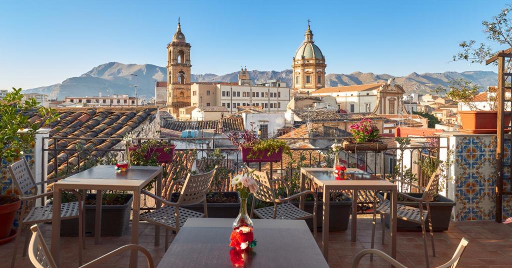 balcón con vistas a la ciudad, mesas y sillas en La Terrazza sul Centro en Palermo