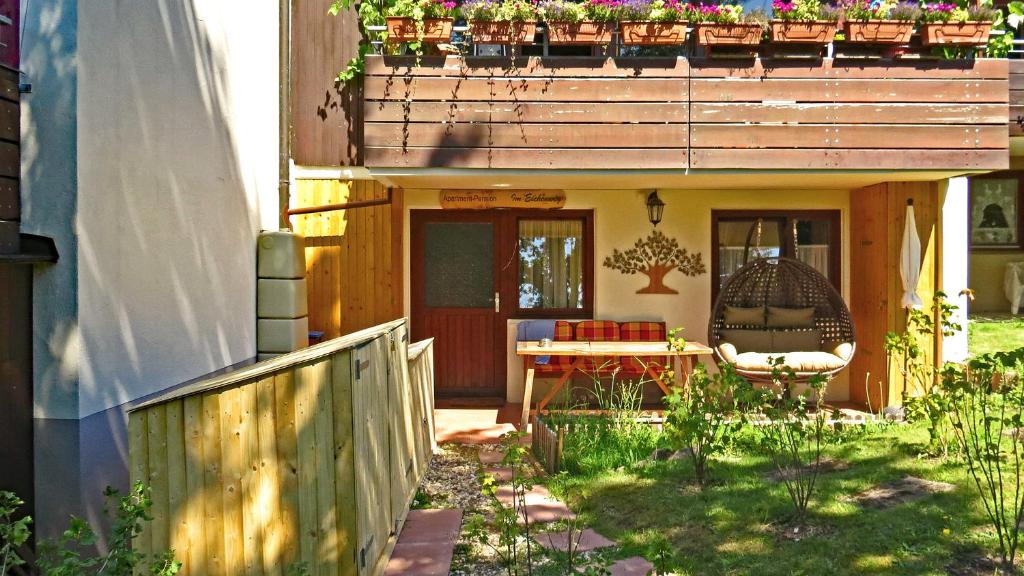 ein kleines Haus mit einer Terrasse und einem Stuhl auf einer Veranda in der Unterkunft Apartment-Pension Im Eichenweg in Waldachtal