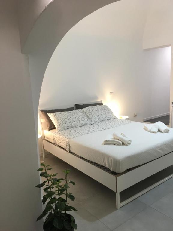 ein weißes Schlafzimmer mit einem weißen Bett mit einem Deckenbogen in der Unterkunft FREE FLAT in Catania
