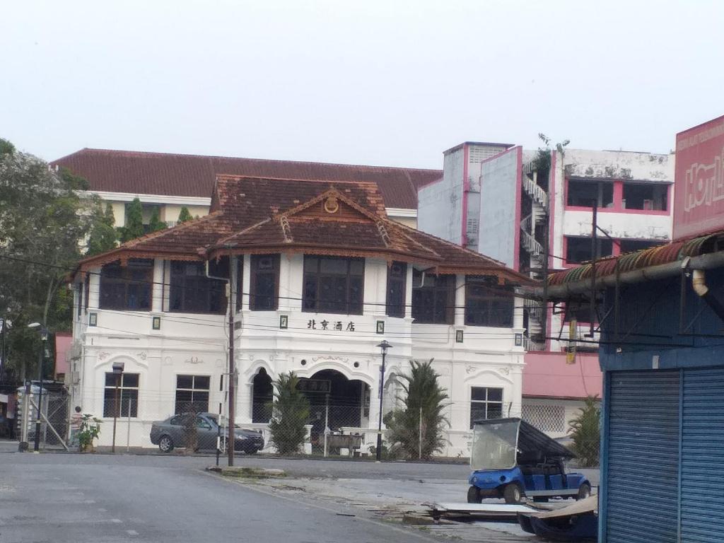 biały budynek z brązowym dachem na ulicy w obiekcie Hotel Peking w mieście Taiping