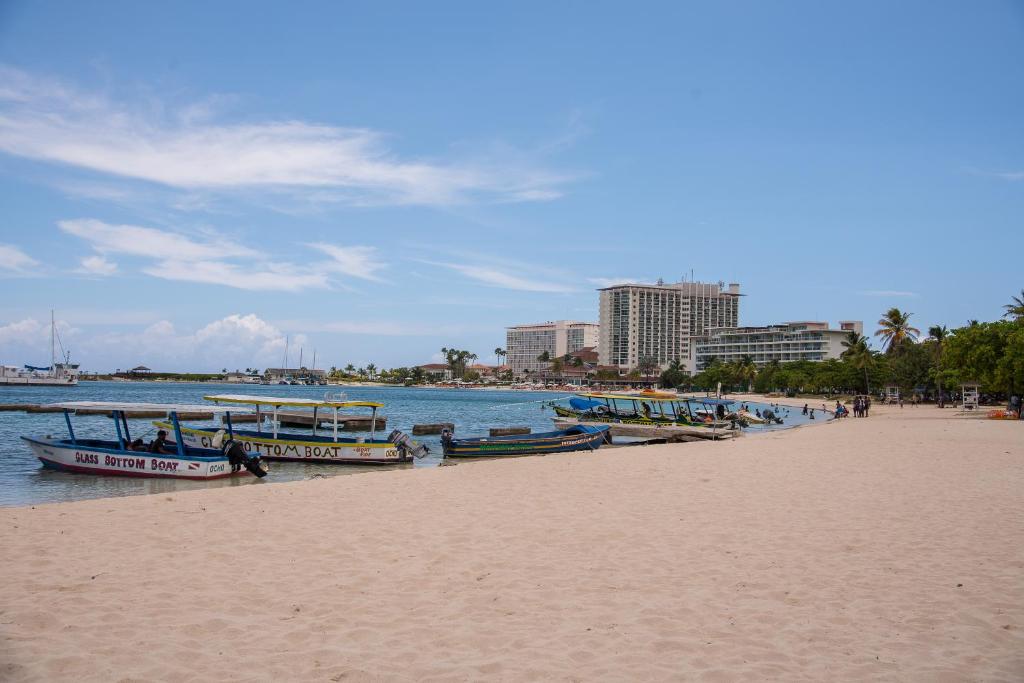 una playa con barcos en el agua y edificios en Ocho Rios Vacation Resort Property Rentals, en Ocho Ríos