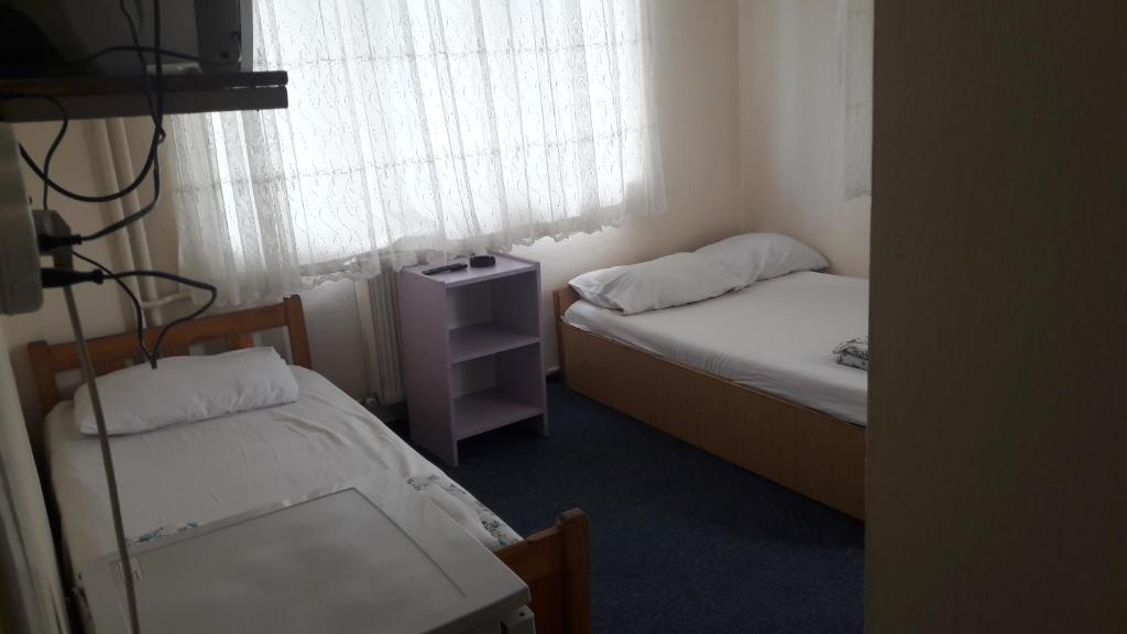 a room with two beds and a table and a window at FİLİZ PANSİYON in Denizli