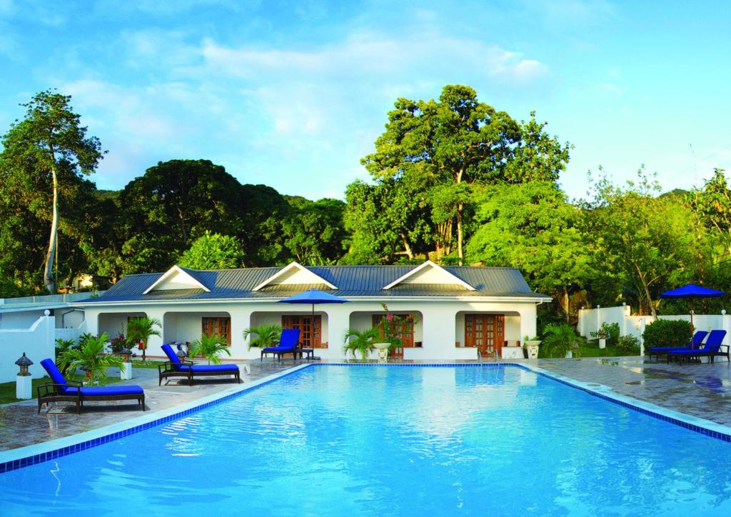 a villa with a swimming pool in front of a house at Britannia Hotel in Grand'Anse Praslin