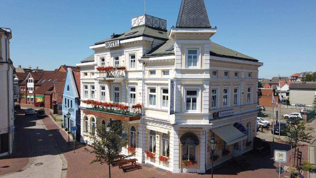 un grand bâtiment blanc avec une tour dans une rue dans l'établissement Hotel Hohenzollernhof, à Cuxhaven