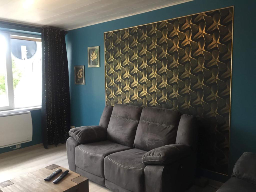 een woonkamer met een bank en een muur bij Les terrasses in Malmedy