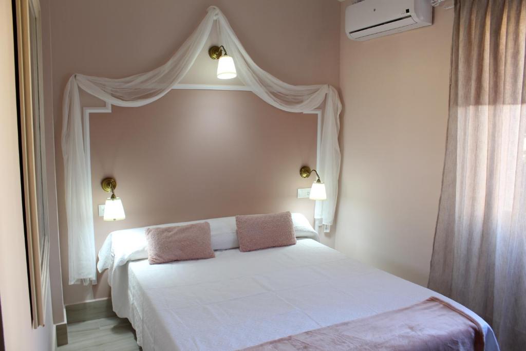 een slaapkamer met een wit bed met 2 kussens erop bij Emperador Augusto in Merida