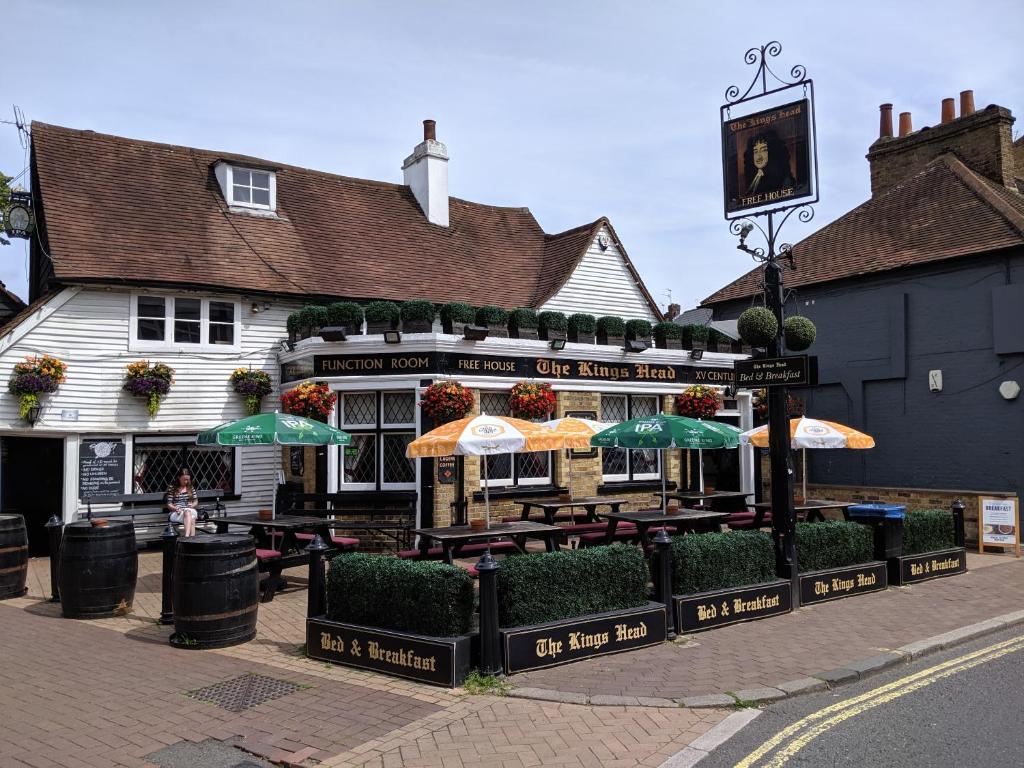 a restaurant with tables and umbrellas on a street at The Kings Head in Bexley