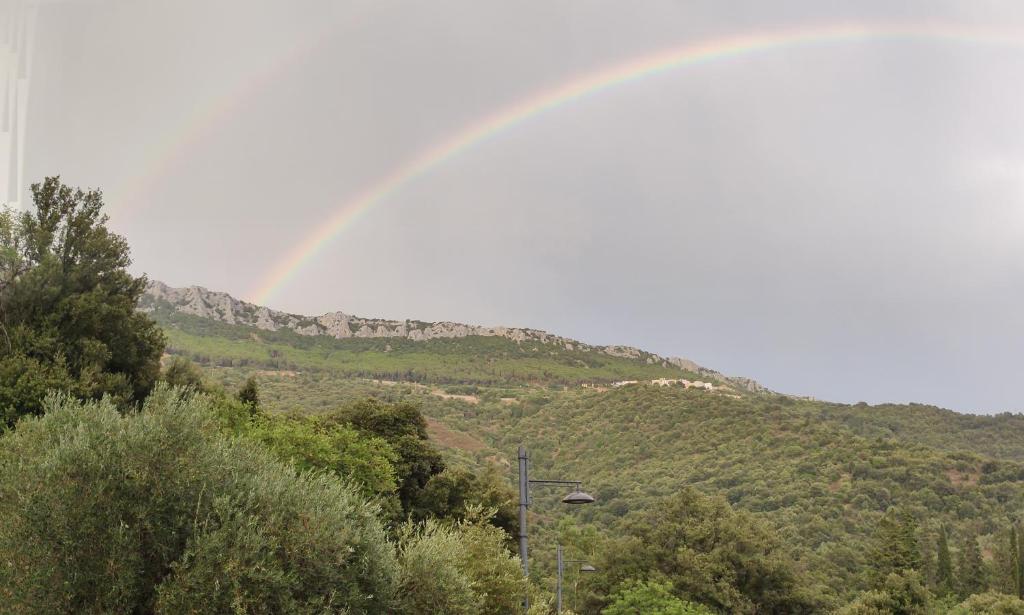een regenboog in de lucht boven een berg bij Sa Dommu 'e su coro in Triei