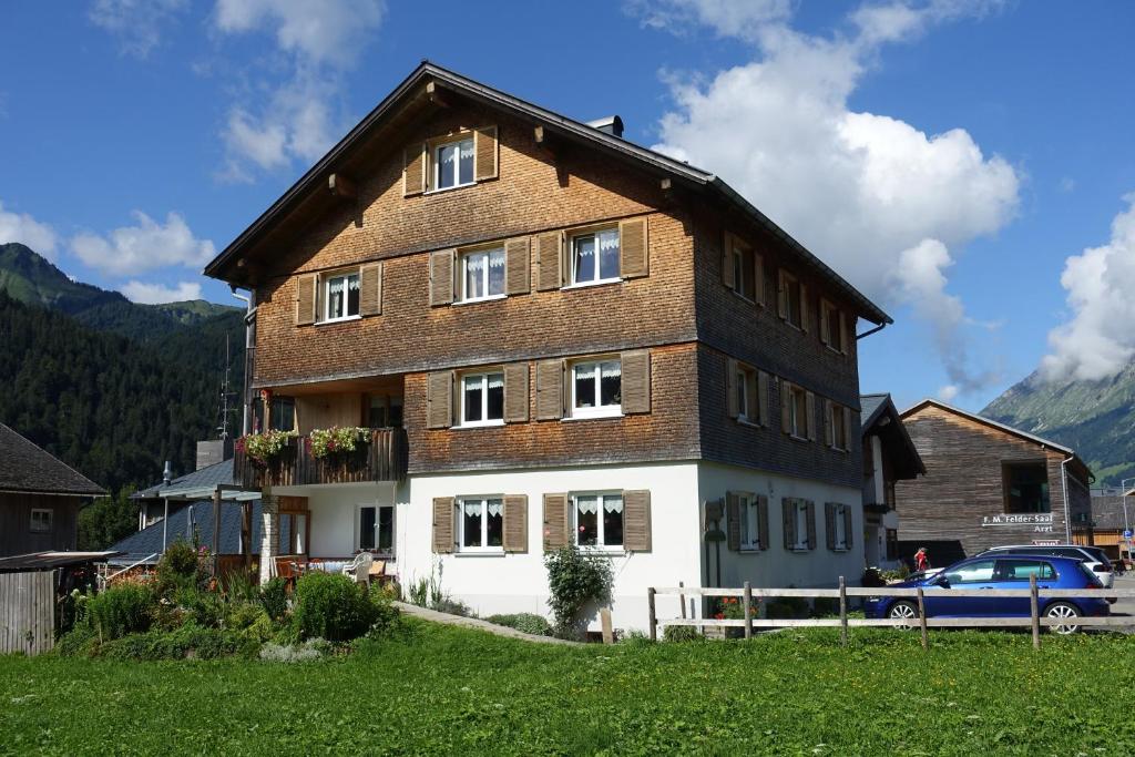 uma casa grande num campo com um carro à frente em Pension Haus Romy em Schoppernau