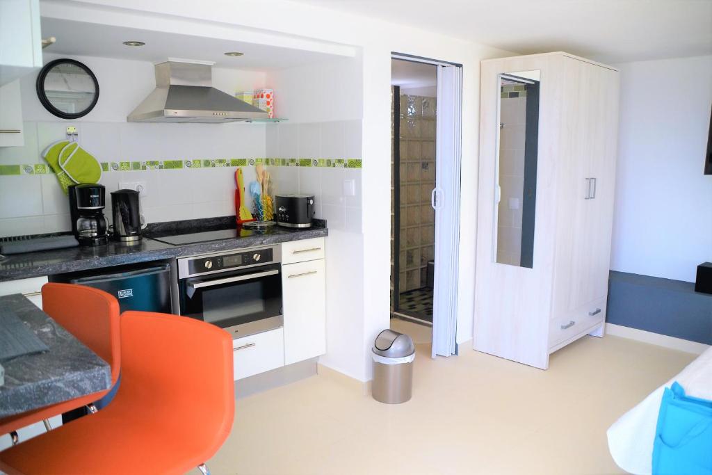 eine Küche mit weißen Schränken und einem orangefarbenen Stuhl in der Unterkunft VIP Caribbean Views 300 meters to the Coral Estate beach in Willibrordus