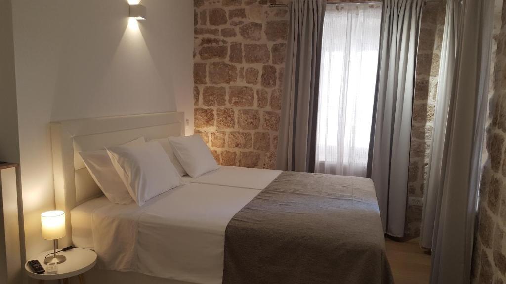 a bedroom with a white bed and a brick wall at Apartments Milion in Korčula