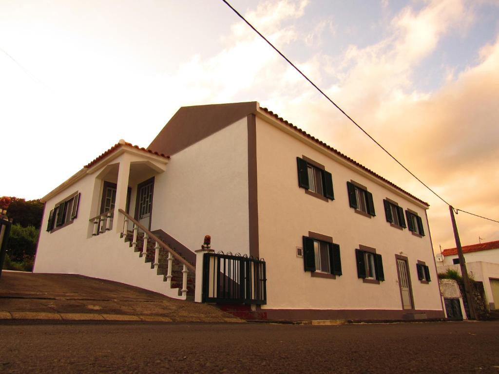 Lajes das Flores的住宿－Casa L&M，街道上一座白色的建筑,有黑色百叶窗