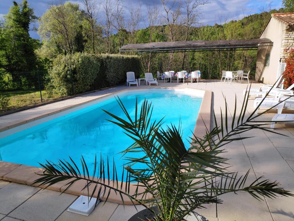 a swimming pool in a backyard with a table and chairs at Villa Les Carlets in Saignon