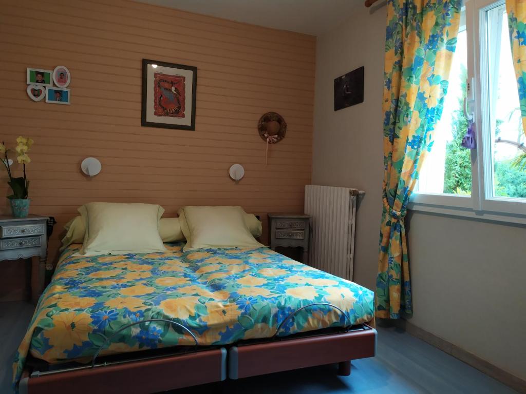 Un dormitorio con una cama con un edredón colorido y una ventana en Chambres Le Mans 24 heures, en Arnage