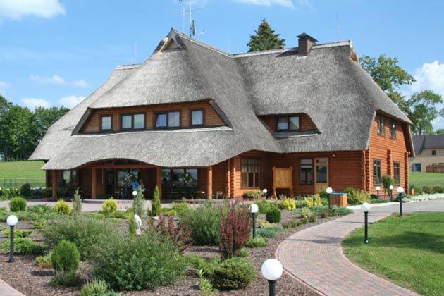 a large house with a thatched roof in a garden at Vonadziņi in Stāmeriena