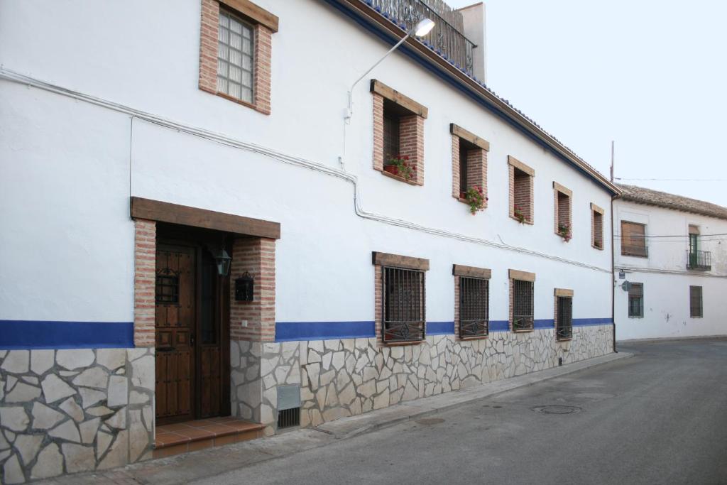un edificio blanco con una puerta y ventanas marrones en Casa Rural La Posada Del Frances, en Villarrubia de Santiago