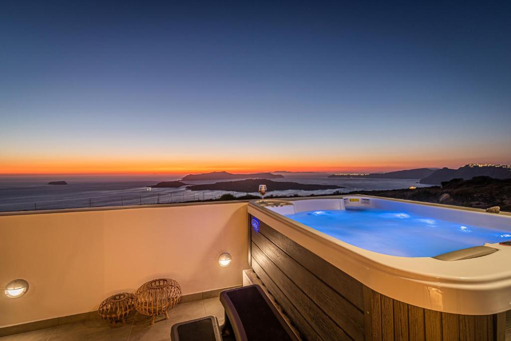 a hot tub on a balcony with a view of the ocean at Caldera Stories private suites in Megalokhori