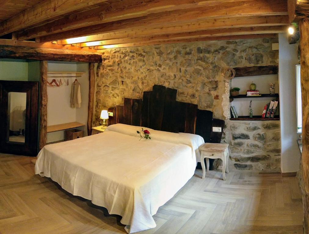 um quarto com uma cama grande numa parede de pedra em Casa rural Abatetxe em Elgóibar