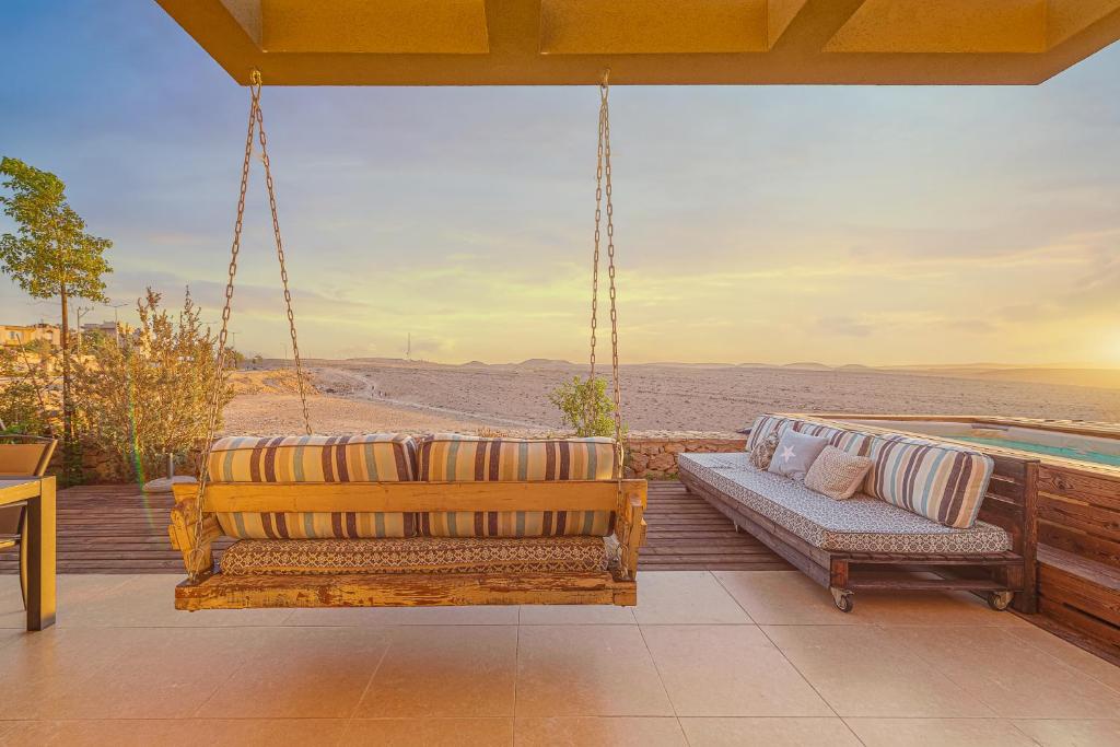 a swing on a porch with a view of the desert at Mitzpush Premium Villa in Mitzpe Ramon