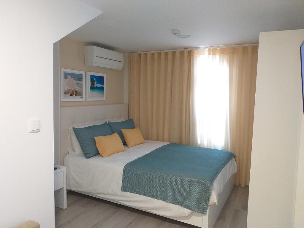 Schlafzimmer mit einem Bett mit blauen und gelben Kissen in der Unterkunft O Palacete in Vila Real