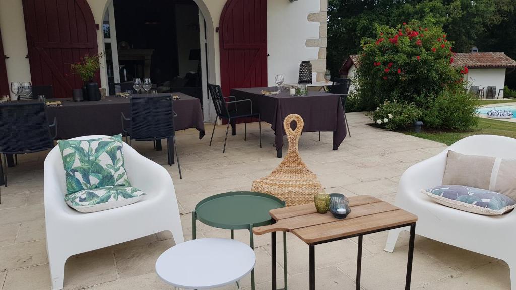 a patio with white chairs and tables and a table at Maison d hotes Lapitxuri in Arcangues