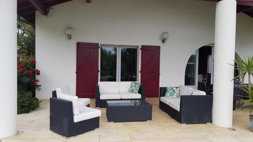 a patio with two white chairs and a table at Maison d hotes Lapitxuri in Arcangues