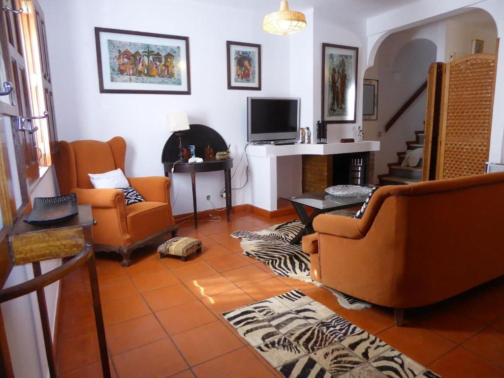 a living room with orange chairs and a fireplace at CASA BERIMBAU in Vila Nova de Milfontes