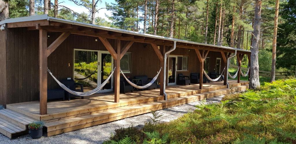 une cabane en bois avec une terrasse couverte dans les bois dans l'établissement Cerību Liedags, à Mērsrags