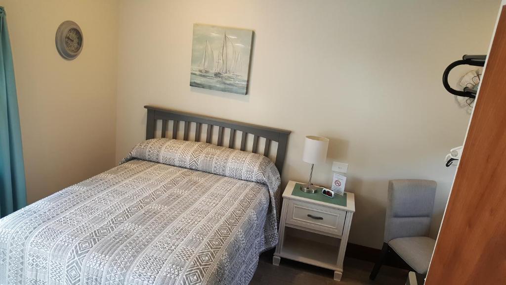 een kleine slaapkamer met een bed en een stoel bij King Phillip motel in Gardner