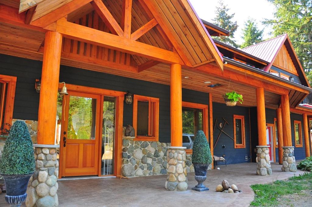 a home with a large wooden house with a porch at Paradise Acres Ranch in Nanoose Bay