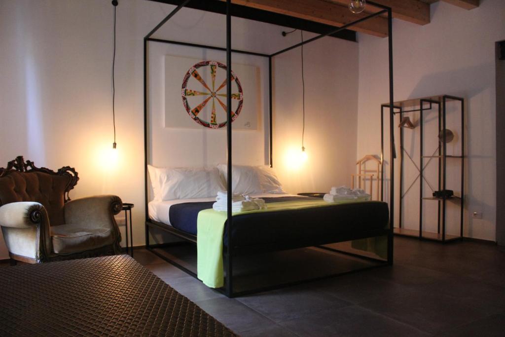 a bedroom with a canopy bed and a chair at Dimore San Nicola in Favara