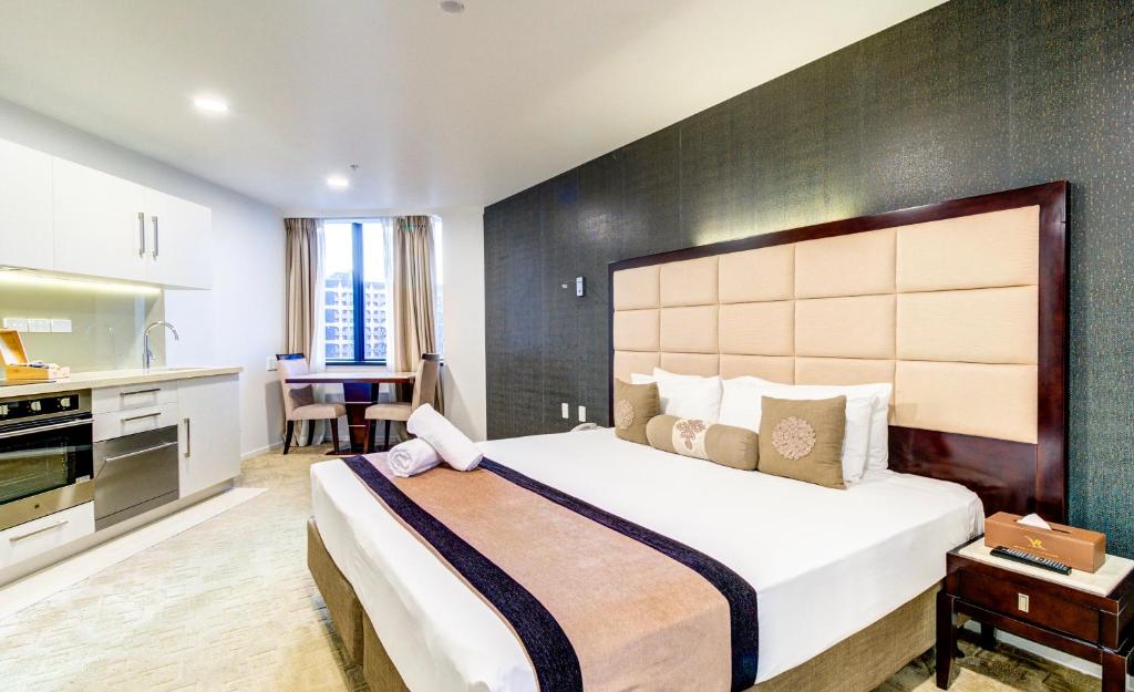 a hotel room with two beds and a television at VR Queen Street Hotel & Suites in Auckland