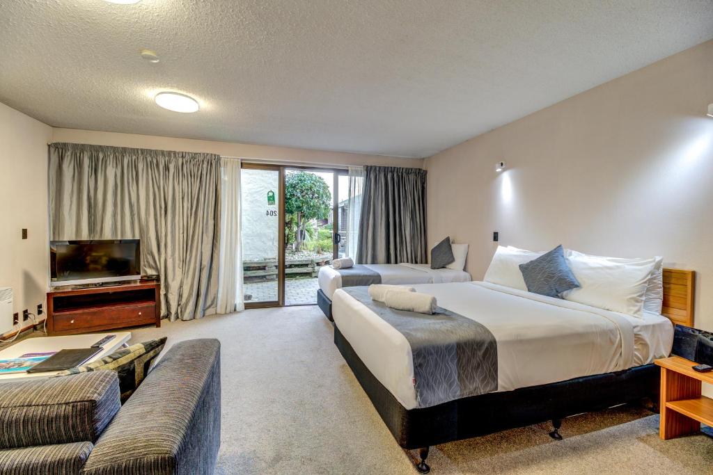 a hotel room with two beds and a couch at The Lofts Apartments in Queenstown