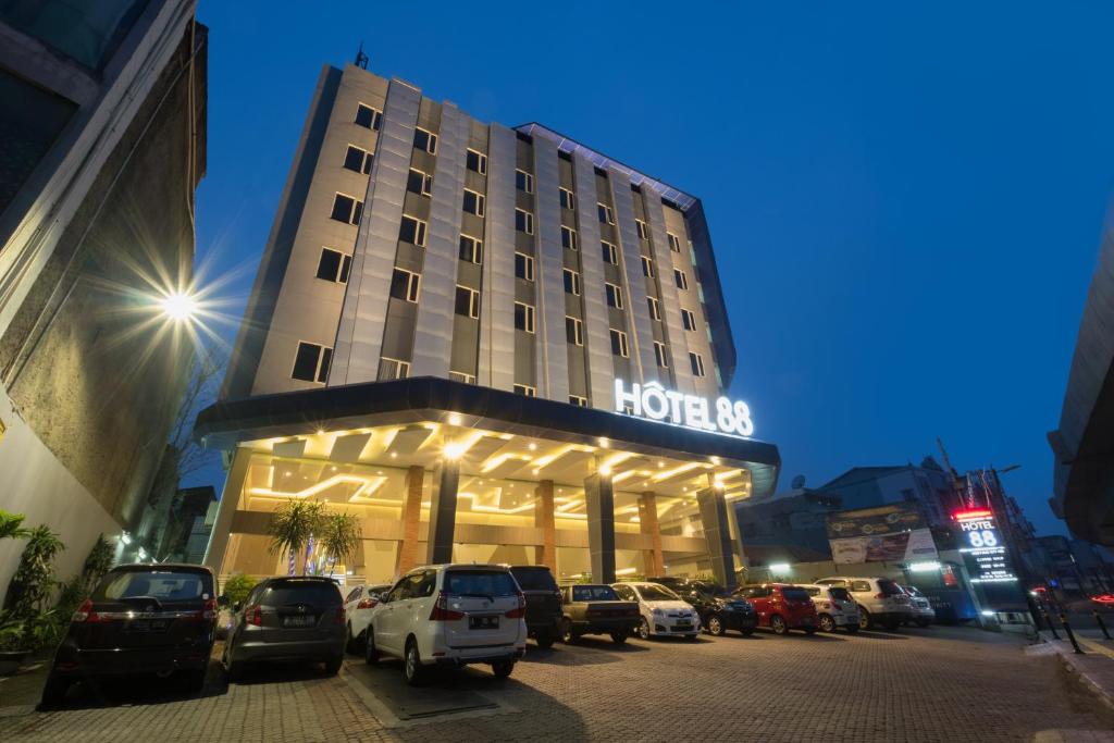 un bâtiment d'hôtel avec des voitures garées devant lui dans l'établissement Hotel 88 ITC Fatmawati Jakarta By WH, à Jakarta