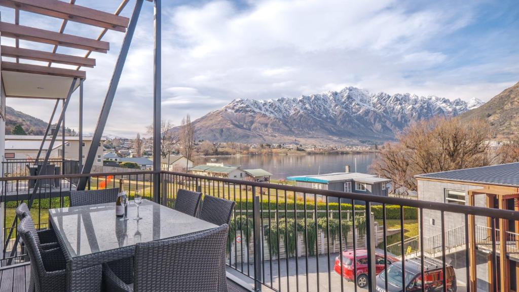 uma varanda com mesa e cadeiras e vista para as montanhas em Marina Quarters 406B em Queenstown