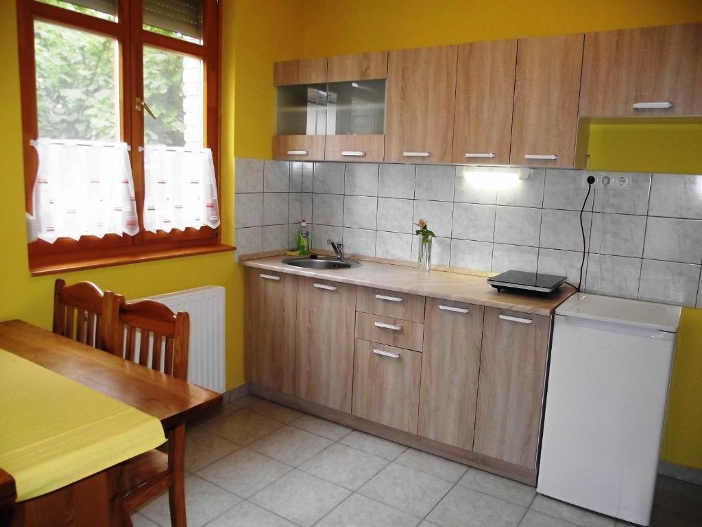 kuchnia z drewnianymi szafkami, zlewem i stołem w obiekcie Mediterrán Vendégház w mieście Kecskemét