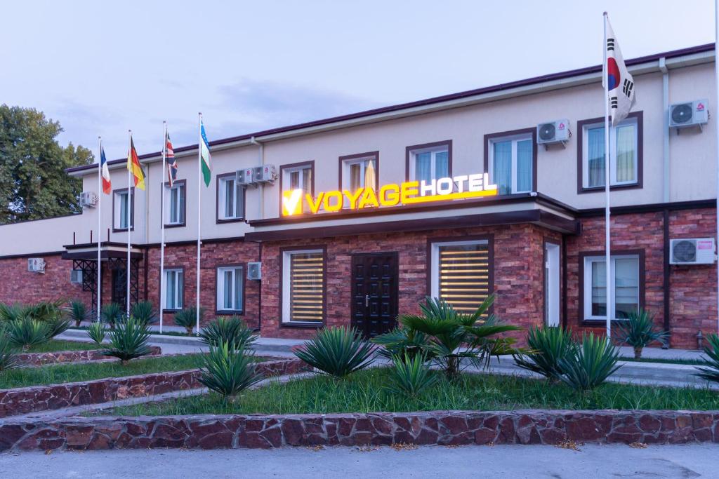 um hotel com bandeiras em frente a um edifício em VOYAGE HOTEL em Fergana