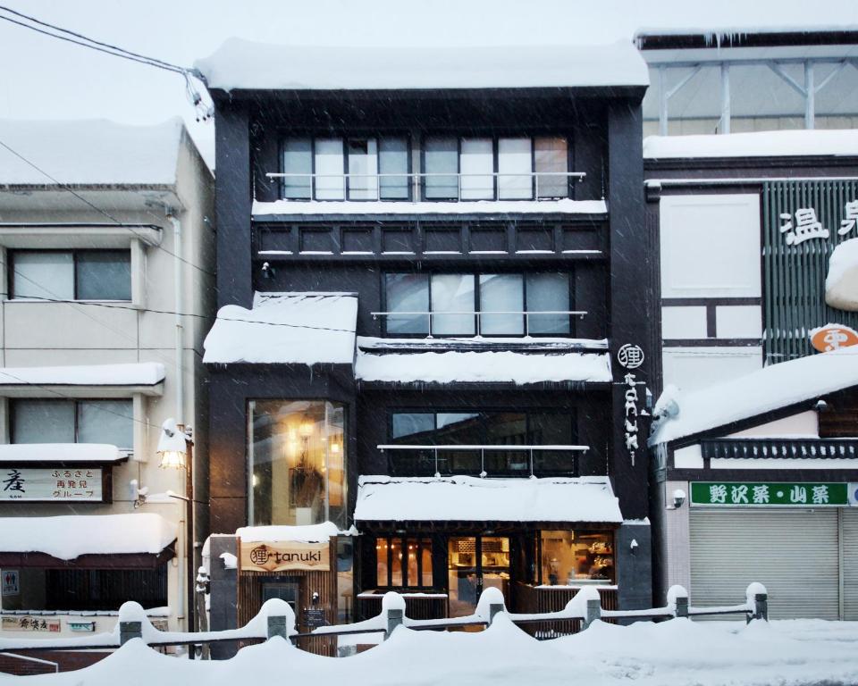 a building covered in snow in a city at Tanuki Nozawa in Nozawa Onsen