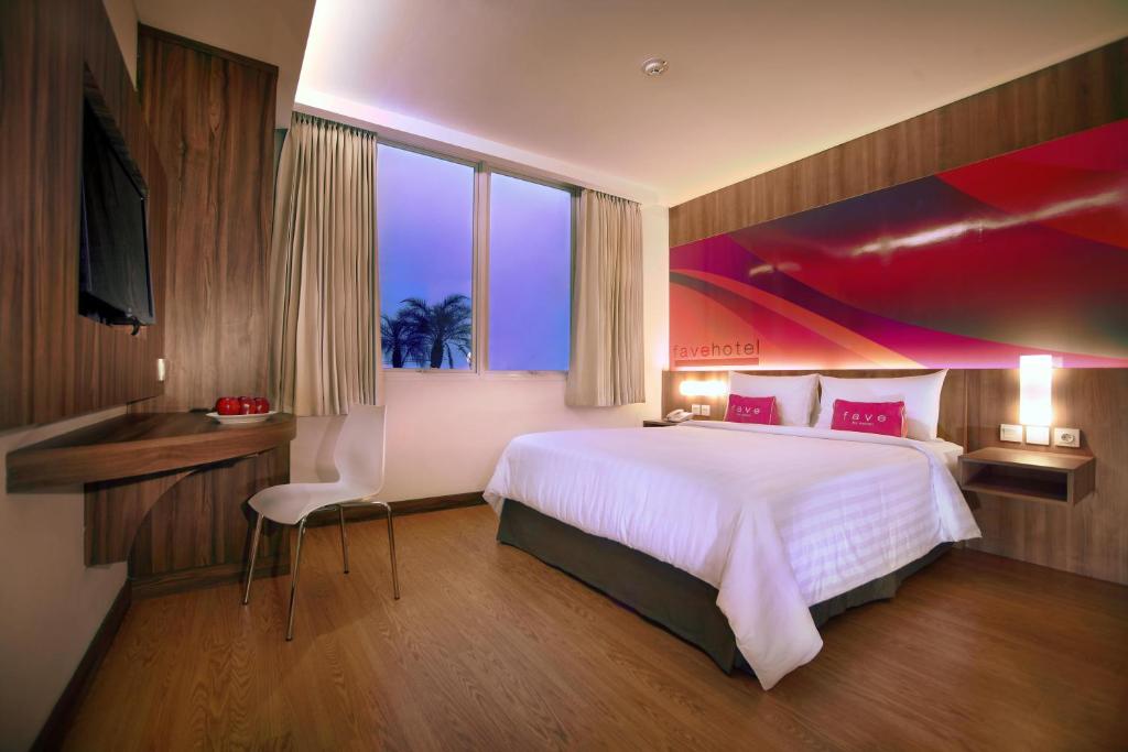 a bedroom with a large bed and a large window at favehotel LTC Glodok in Jakarta