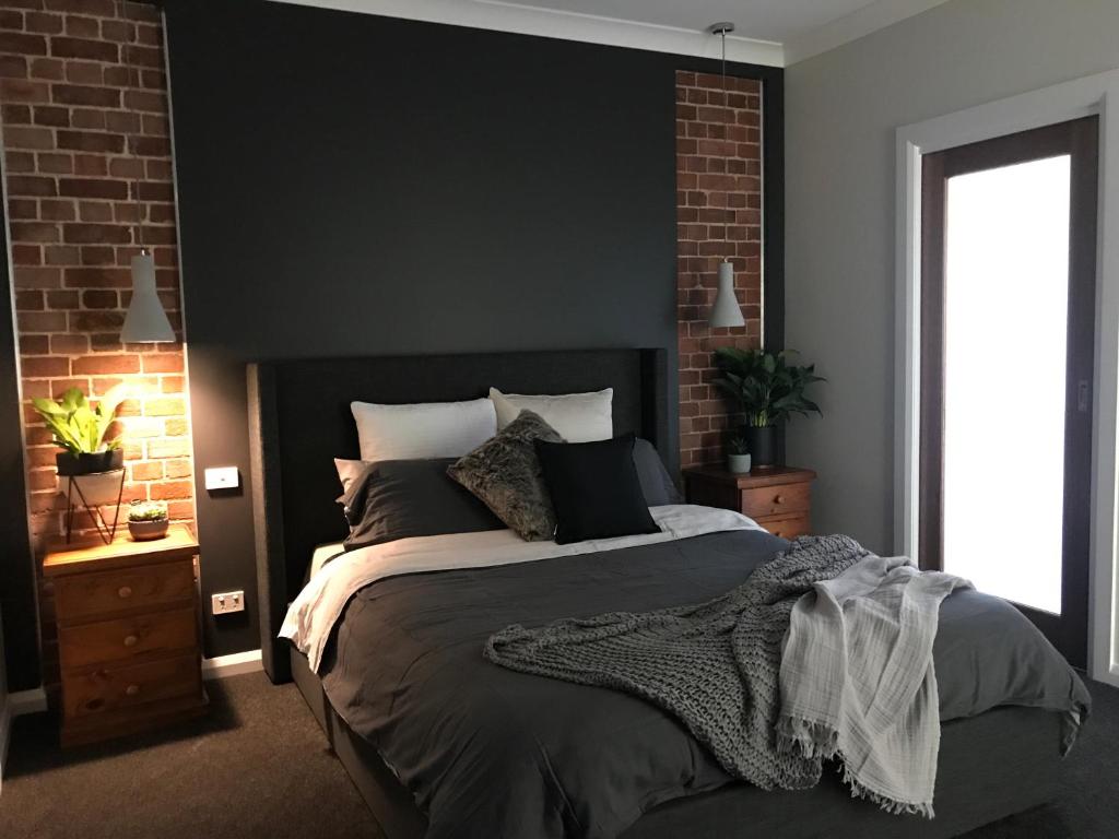 um quarto com uma cama grande e uma parede de tijolos em Executive Villa, private 2 bedroom in ideal location em Bathurst
