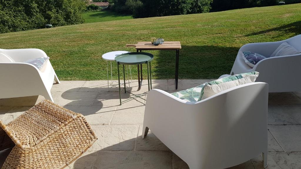a patio with white chairs and a table and a field at Maison d hotes Lapitxuri in Arcangues