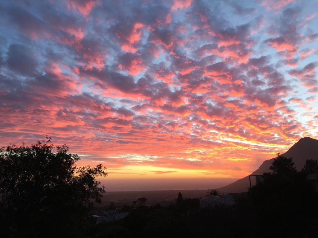 um pôr do sol com nuvens coloridas no céu em Sapphire Studio em Noordhoek