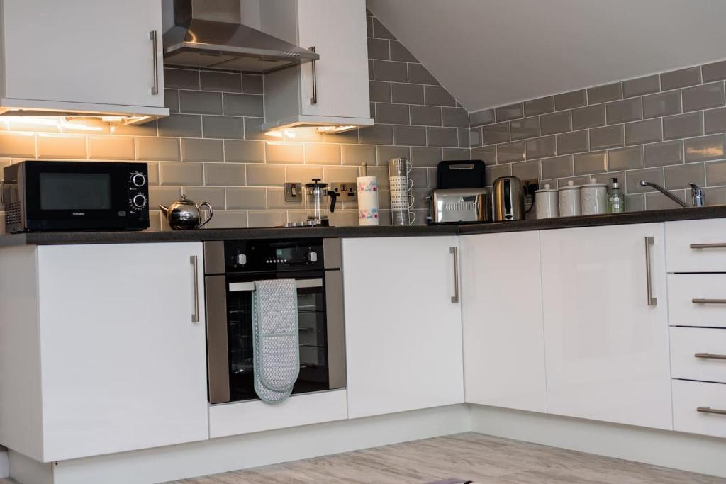 Biała kuchnia z białymi szafkami i urządzeniami w obiekcie Mc Callstown House Apartment w mieście Ballyclare