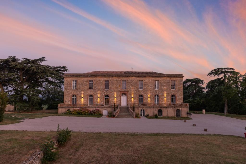 a large brick building with a sunset in the background at Château de Tauzies, The Originals Relais in Gaillac