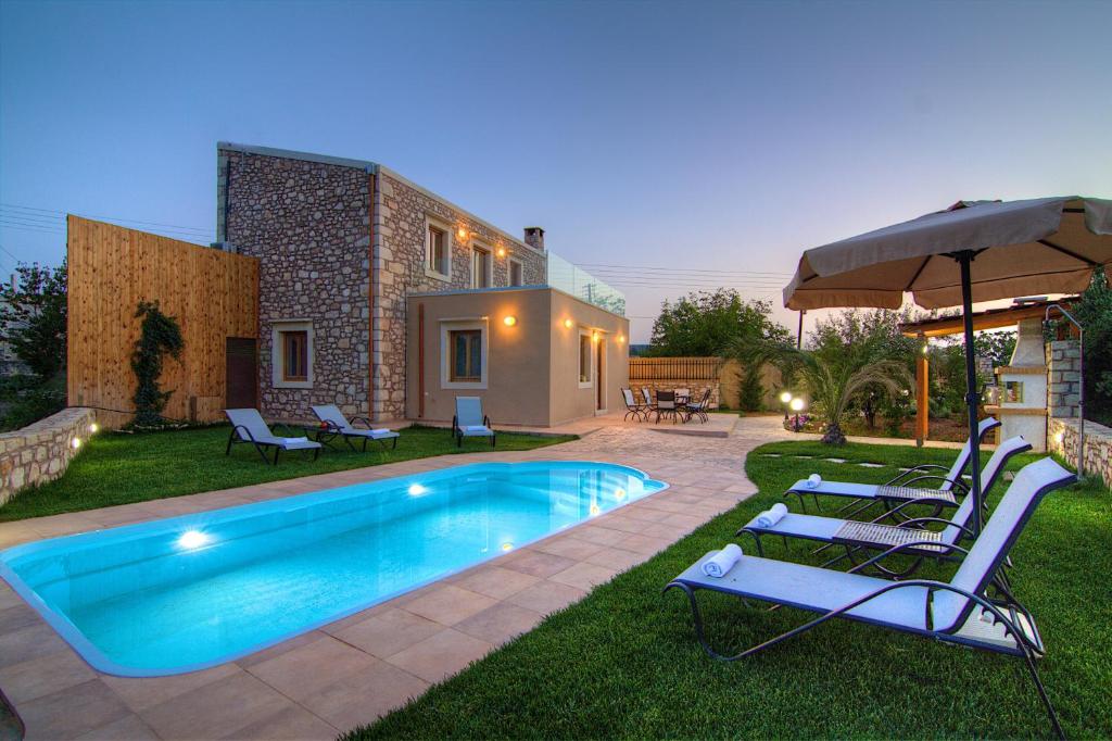 MargarítaiにあるGreen Paradise Villaのラウンジチェアとパラソル付きのスイミングプールを併設しています。