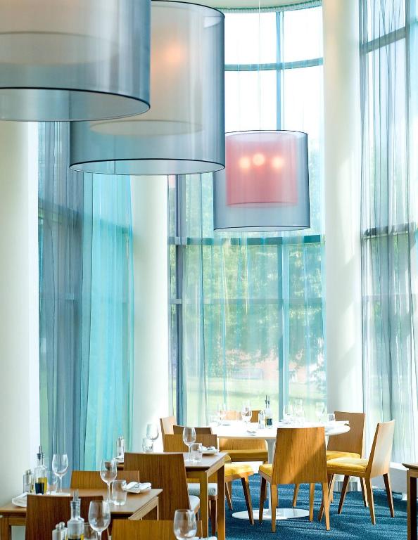 a restaurant with tables and chairs and large windows at Radisson Blu Hotel, Trondheim Airport in Stjoerdal