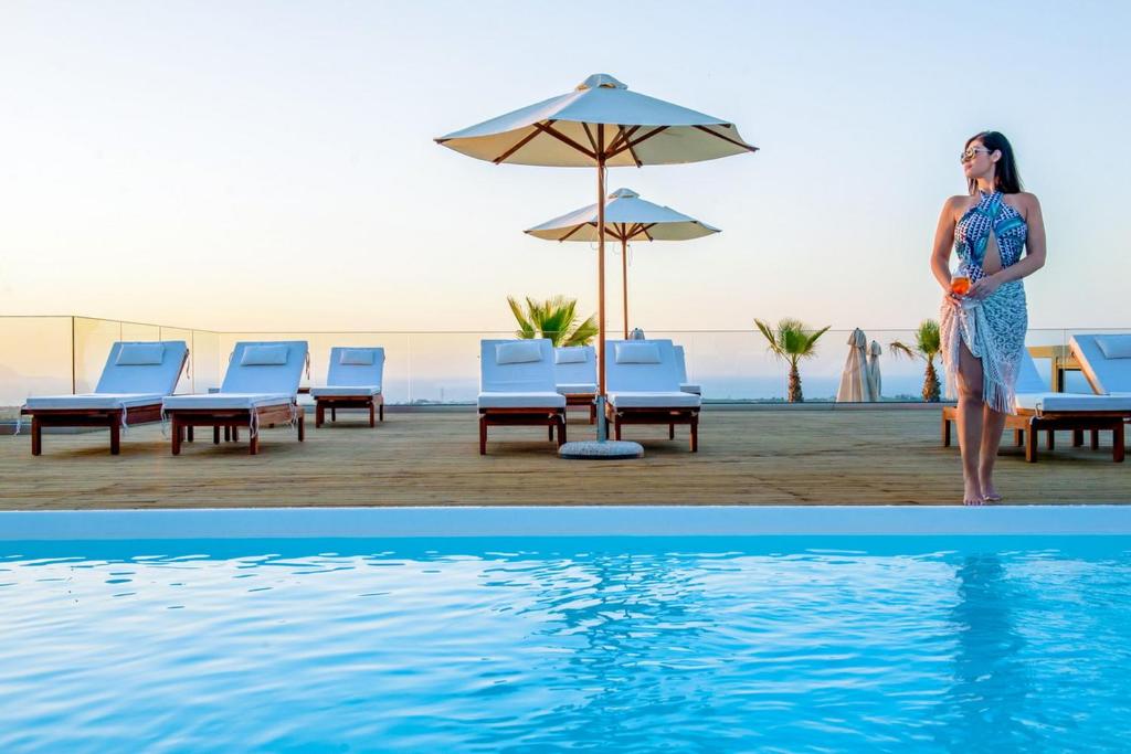 een vrouw naast een zwembad in een resort bij Villaggio Boutique Hotel Hersonissos - Adults Only in Chersonissos