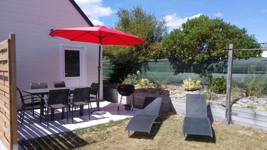 um pátio com uma mesa e cadeiras e um guarda-sol vermelho em Chalet Les dauphins em Saint-Georges-de-la-Rivière