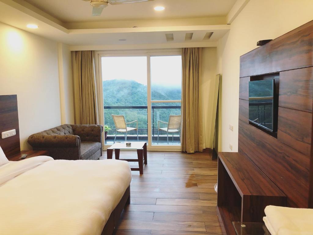 a hotel room with a bed and a large window at Hotel Chail Residency in Chail