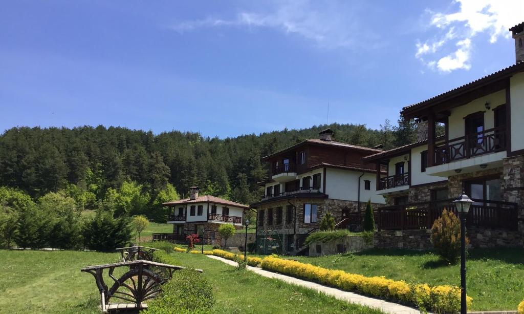 um grupo de casas numa colina com um campo verde em Хотел Планински кът em Dorkovo